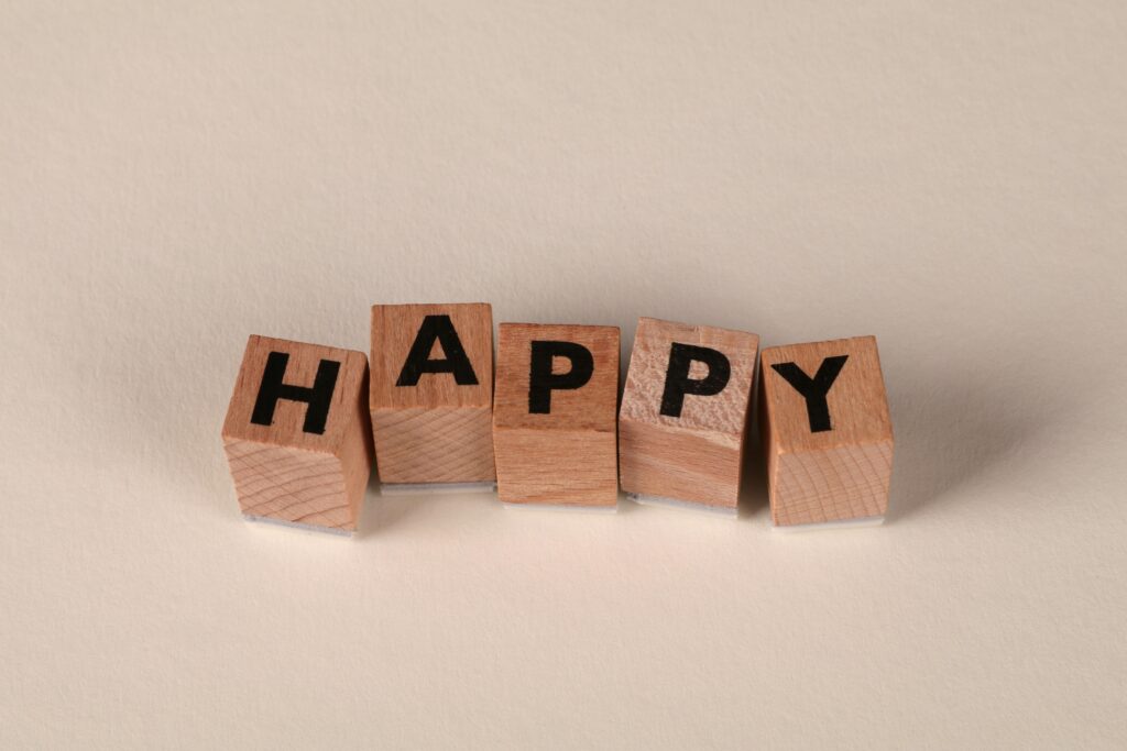 Wooden blocks with the word 'Happy' on a light neutral background. Perfect for themes of joy and positivity.
