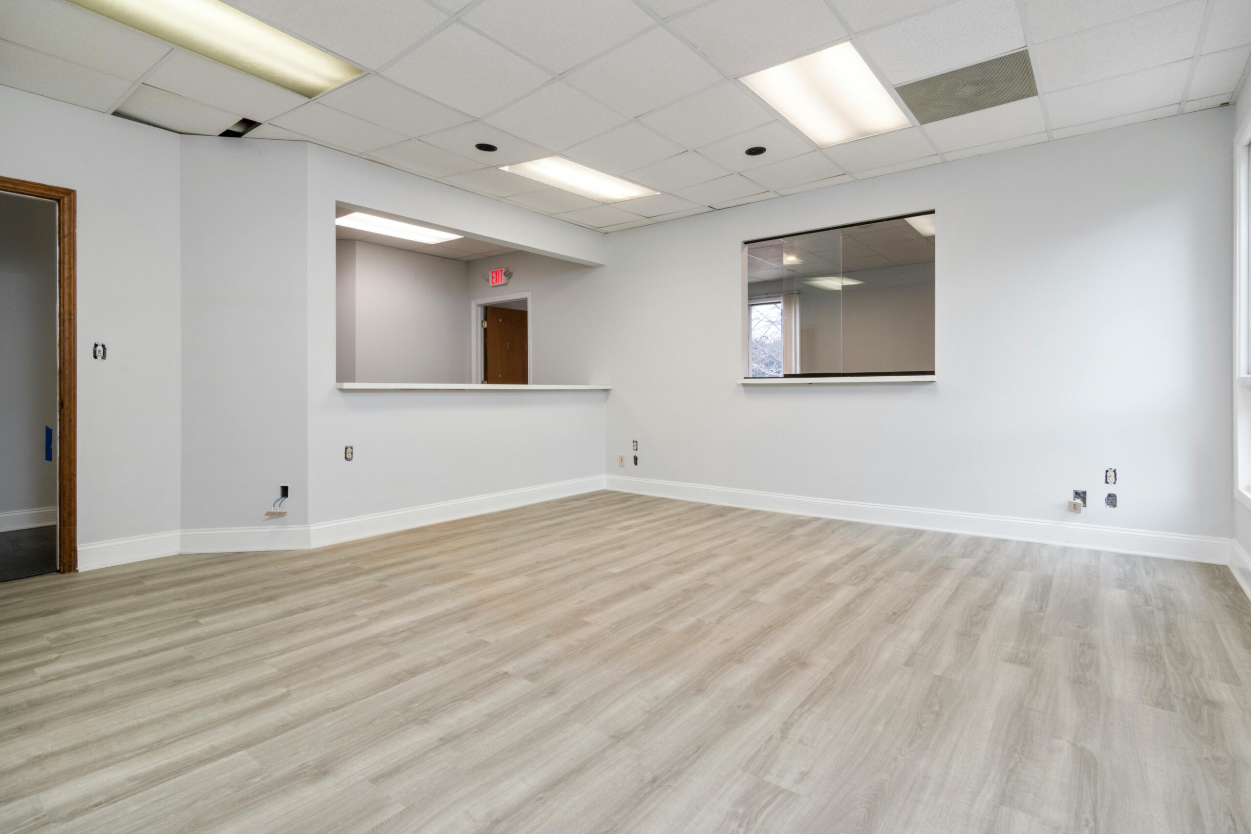 Modern and spacious empty room with wooden flooring and recessed lighting.